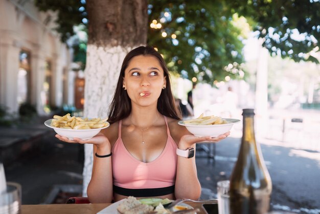 Les jeunes femmes tiennent des frites sur des assiettes blanches Café de la rue