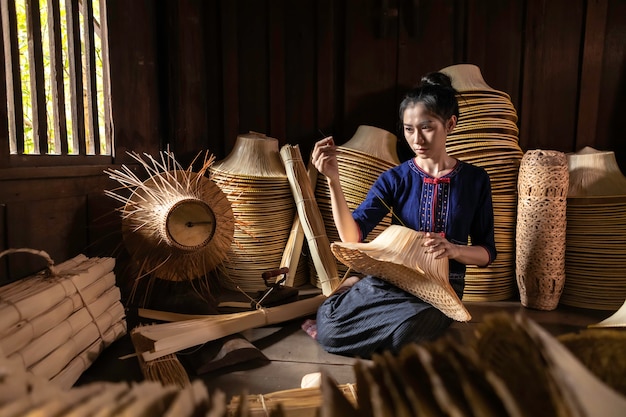 De jeunes femmes tissent dans un panier à la main en Thaïlande.