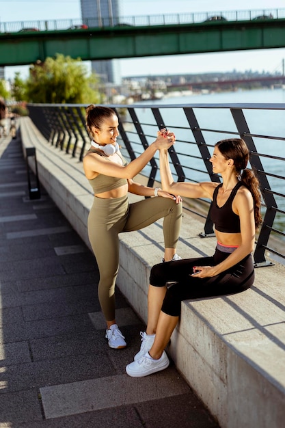 Jeunes femmes en vêtements de sport faisant de l'exercice sur une promenade fluviale