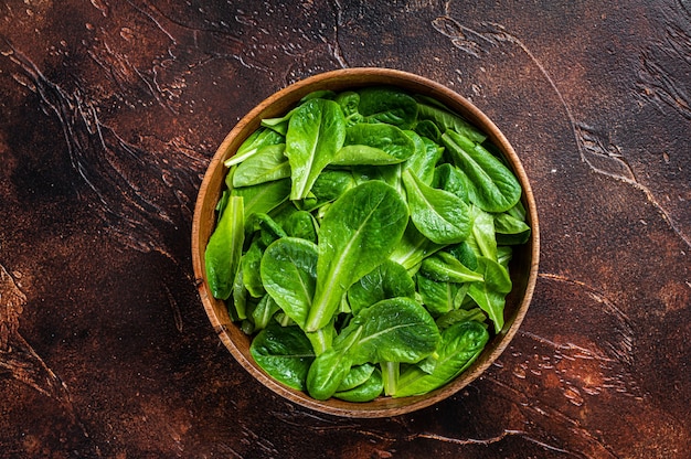 Les jeunes feuilles de salade verte romain dans une assiette en bois