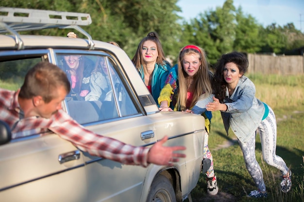 Les jeunes filles gaies poussent une vieille voiture Femmes dans le style des années 90