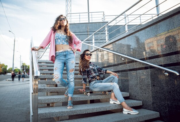 Jeunes filles avec planche à roulettes assis sur les escaliers