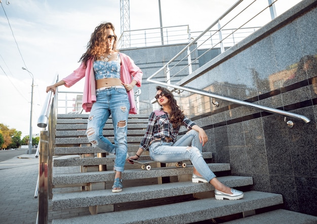 Jeunes filles avec planche à roulettes assis sur les escaliers