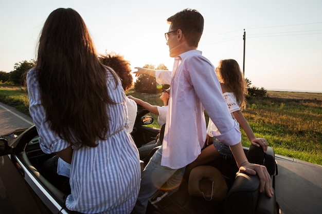 Les jeunes gars sont assis dans un cabriolet noir sur la route de campagne par une journée ensoleillée. .