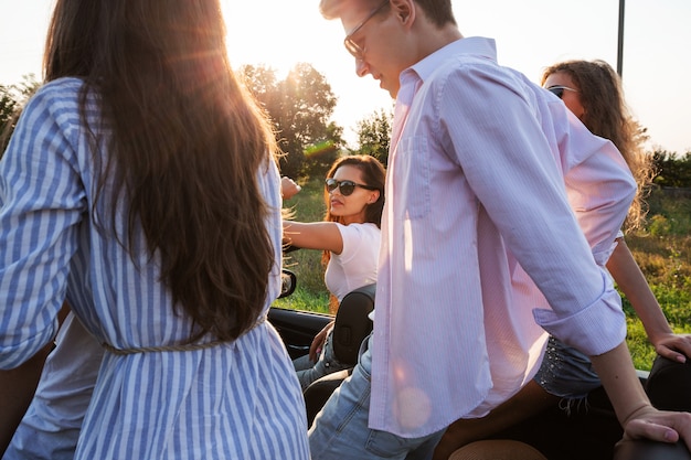 Les jeunes gars sont assis dans un cabriolet noir sur la route de campagne par une journée ensoleillée. .