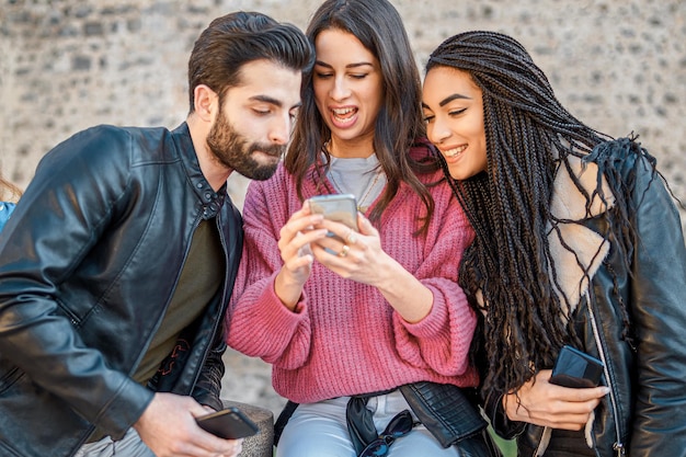 Les jeunes de la génération z parcourent le contenu des médias sociaux en ligne avec un smartphone. Zoomers utilisant la technologie du téléphone ensemble à l'extérieur.