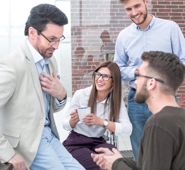 Les jeunes gens d'affaires parlent et sourient pendant la pause-café au bureau