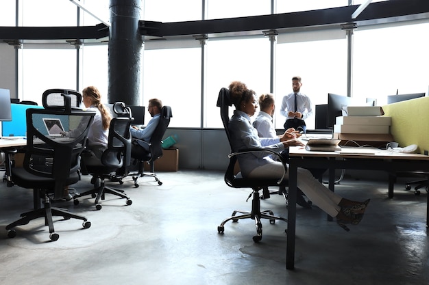 Les jeunes gens d'affaires en tenue de soirée utilisent la technologie moderne tout en travaillant au bureau.