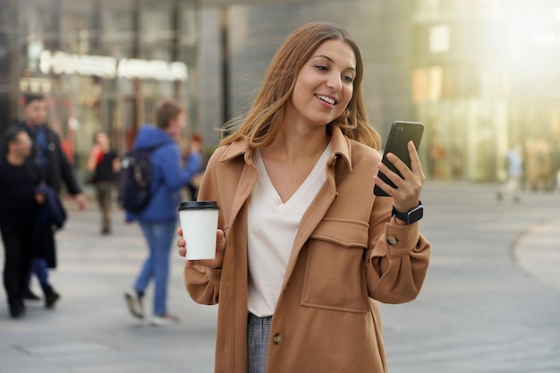 Les jeunes gens d'affaires. Utilisation de smartphone. Café à emporter. Montre intelligente. Achats du vendredi noir. Noël. Arrière-plan flou de personnes.