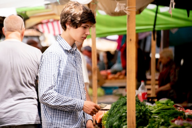 Photo les jeunes gens choisissent des légumes frais et mûrs au marché en plein air et les achètent