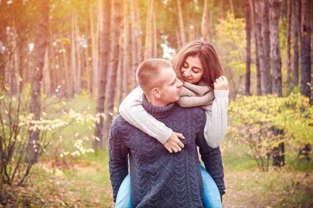 Jeunes gens heureux. Le mec porte sa petite amie sur le dos, elle rigole. Le concept de l&#39;amour.