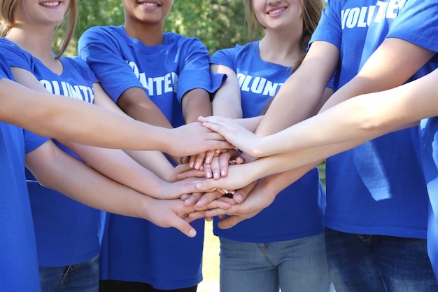 Photo jeunes gens mettant les mains ensemble à l'extérieur. concept de bénévolat