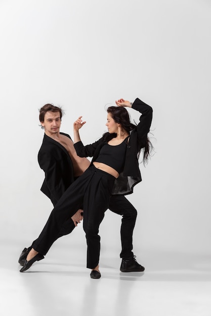 Jeunes et gracieux danseurs de ballet dans un style noir minimal isolé sur fond de studio blanc