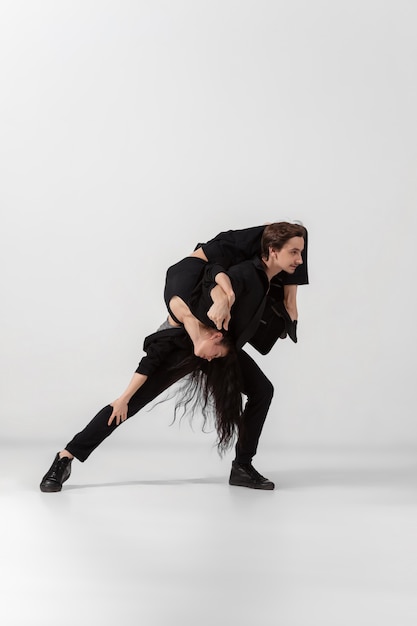 Jeunes et gracieux danseurs de ballet dans un style noir minimal isolé sur fond de studio blanc