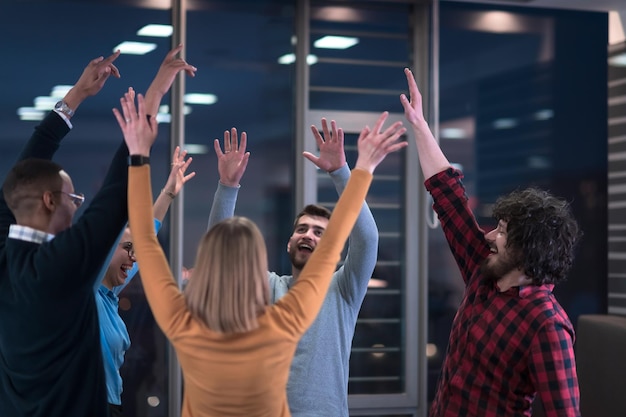 Les jeunes hommes d'affaires multiethniques ravis s'amusent à célébrer le succès ou la victoire partagés de l'entreprise dans