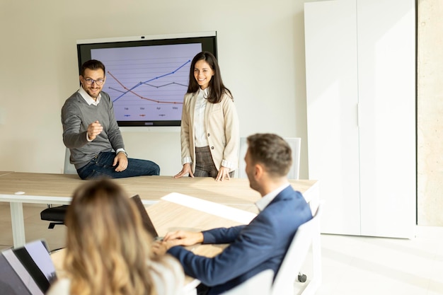 Jeunes hommes d'affaires présentant une stratégie de projet montrant des idées sur un tableau blanc interactif au bureau