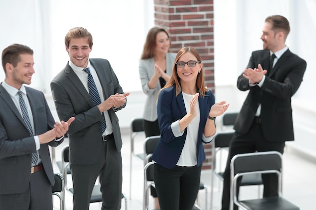 De jeunes hommes d'affaires se tiennent au bureau en souriant et en applaudissant