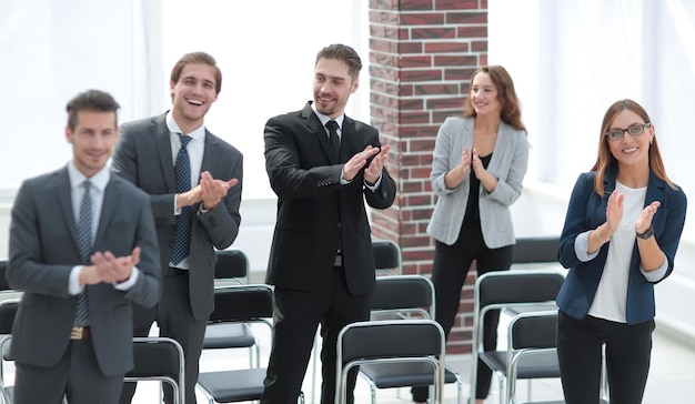 De jeunes hommes d'affaires se tiennent au bureau en souriant et en applaudissant