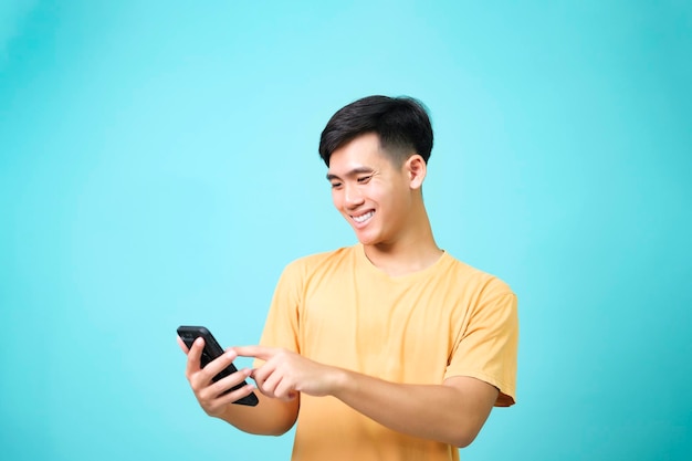 Jeunes hommes asiatiques portant des vêtements décontractés souriant à l'aide du téléphone