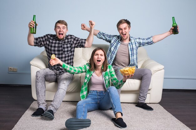 Les jeunes hommes boivent de la bière, mangent des pizzas et encouragent le football