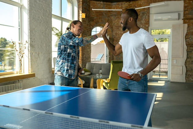 Jeunes hommes jouant au tennis de table en milieu de travail s'amusant