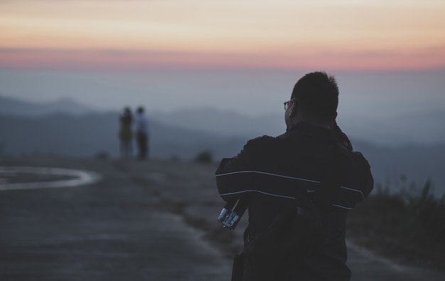 Les jeunes hommes à prendre des photos d'amoureux soir coucher de soleil faible lumière