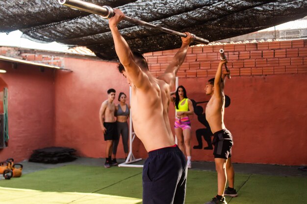 Des jeunes hommes s'arrachent pendant que leurs amis se reposent. Entraînement cross-fit.