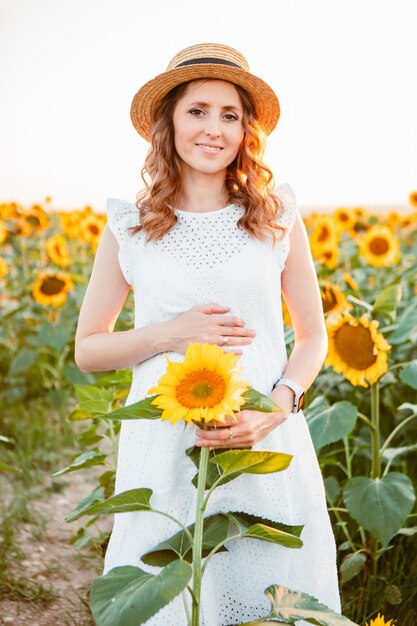 Jeunes jolies femmes enceintes tirant sur un champ de tournesols. espace de copie