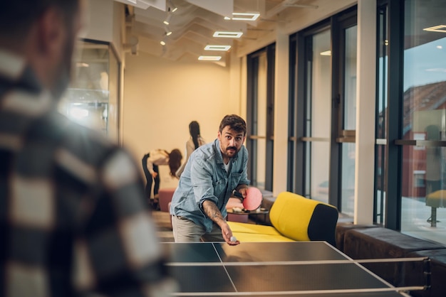 Photo jeunes jouant au tennis de table au bureau au travail