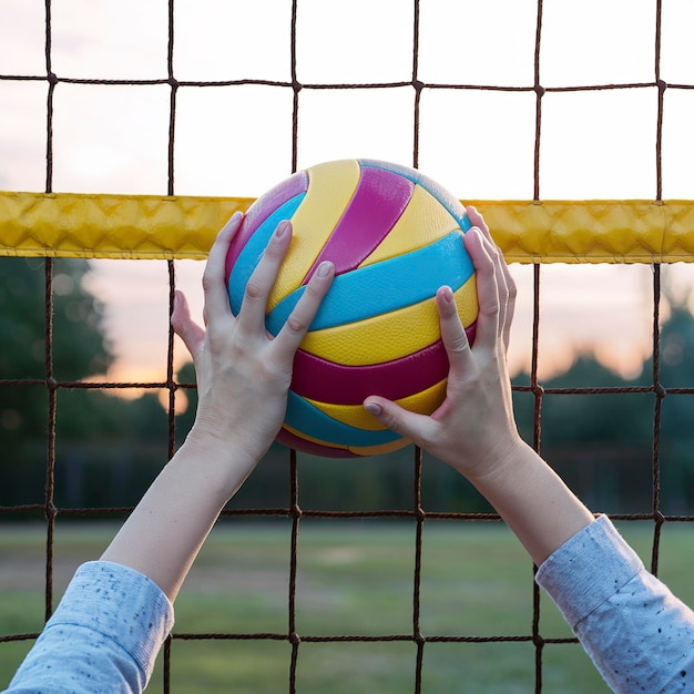 Photo des jeunes mains inconnues jouant au volley-ball au filet.