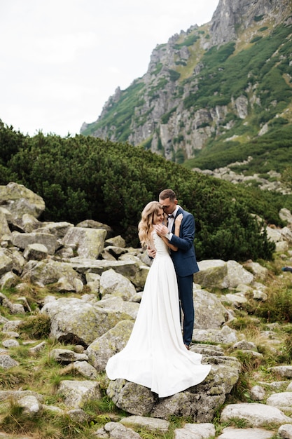 Jeunes mariés au jour du mariage en marchant à l'extérieur sur la nature du printemps. Couple nuptial, heureux jeune femme et homme embrassant dans un parc verdoyant.