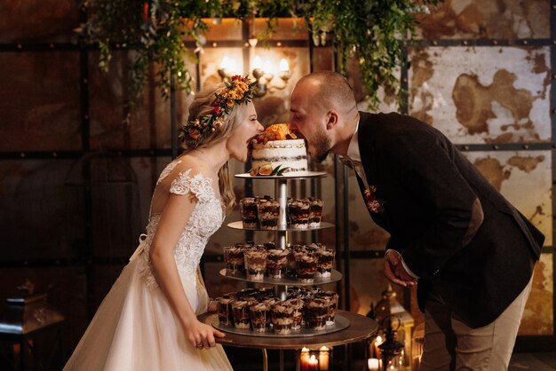 Les jeunes mariés coupent, rient et goûtent joyeusement le gâteau de mariage