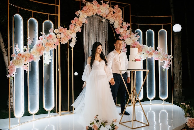 Les jeunes mariés coupent, rient et goûtent joyeusement le gâteau de mariage