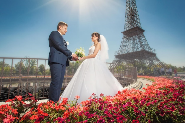 Jeunes mariés dans un parc d'été moderne près d'une copie de la Tour Eiffel