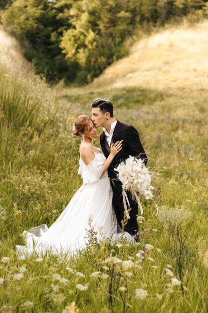 Photo les jeunes mariés du couple de mariage s'embrassent et s'embrassent tendrement sur le fond des collines