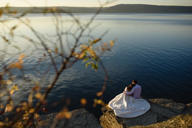 Jeunes mariés étant romantique près d'un lac