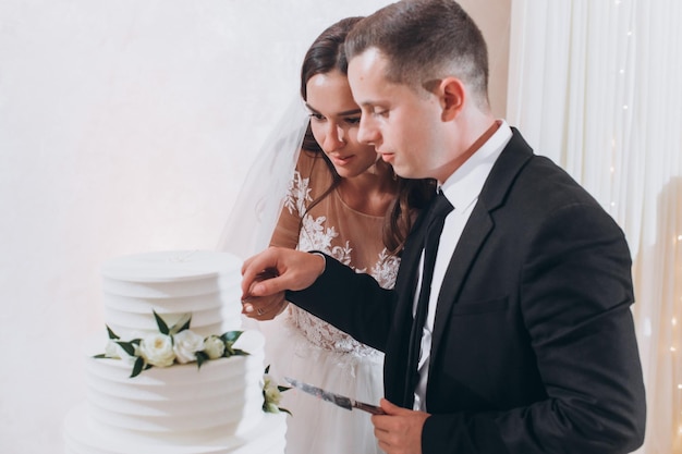 Les jeunes mariés heureux coupent le gâteau