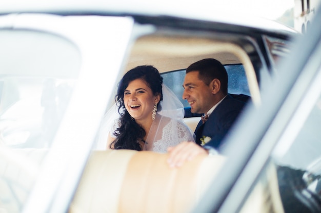 Jeunes Mariés à L'intérieur D'une Voiture Classique. Ils Sont Heureux.