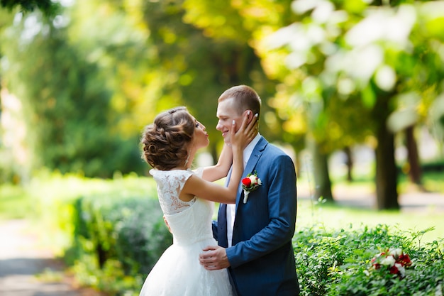 Jeunes mariés le jour de leur mariage, marchant en plein air dans la nature.