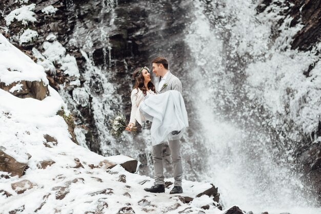 Jeunes mariés sur le mur d'une cascade de montagne