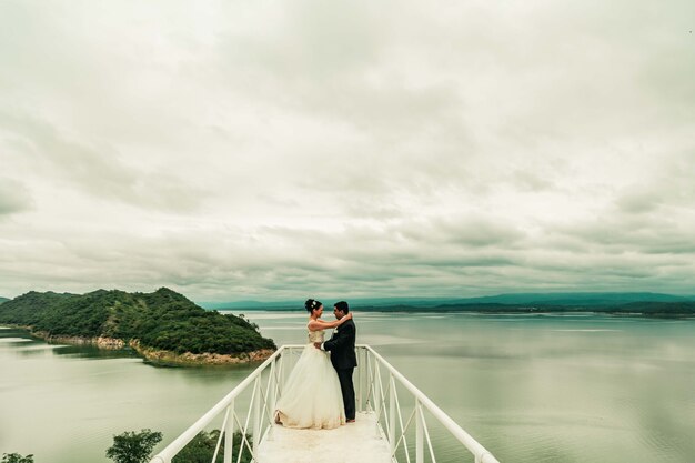 Jeunes mariés sur un pont au bord de la mer proposition de mariage