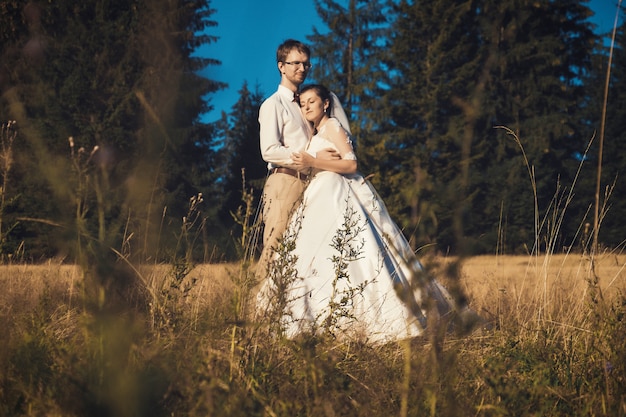 jeunes mariés posant sur un champ
