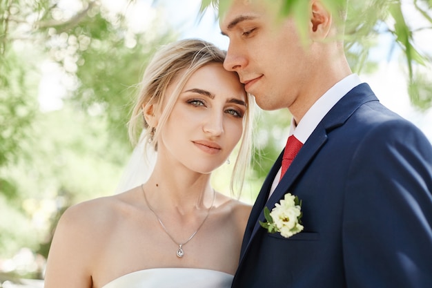 Les jeunes mariés se promènent dans la nature dans le parc après la cérémonie de mariage