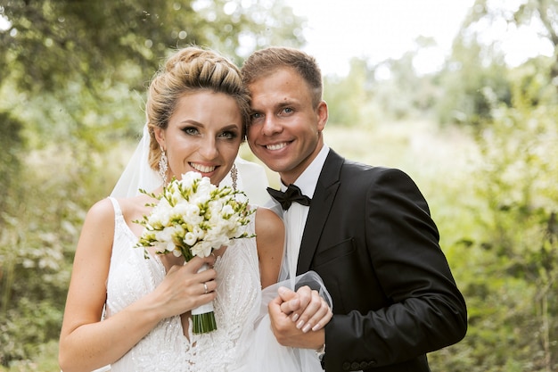 Jeunes mariés se serrant dans la rue de la vieille ville. Couple de mariage amoureux. Robe de luxe en strass. Jours d'été chauds.