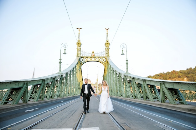 Jeunes mariés se serrant dans la rue de la vieille ville. Couple de mariage amoureux. Robe de luxe en strass.