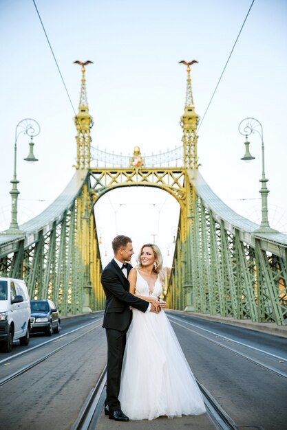 Jeunes mariés se serrant dans la rue de la vieille ville. Couple de mariage amoureux. Robe de luxe en strass.