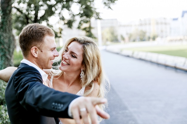 Jeunes mariés se serrant dans la rue de la vieille ville. Couple de mariage amoureux. Robe de luxe en strass.