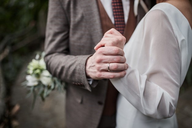 Jeunes mariés se tenant la main à l'extérieur, thème du mariage