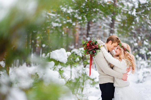 Photo jeunes mariés sont assis sur le journal dans la forêt d'hiver. fermer. cérémonie de mariage d'hiver.