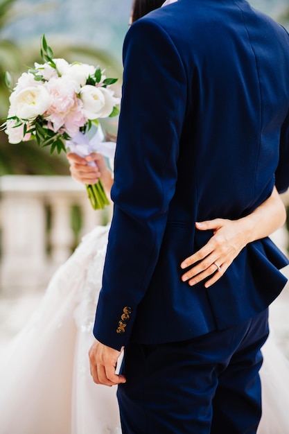 Jeunes mariés tenant ensemble le bouquet de mariage